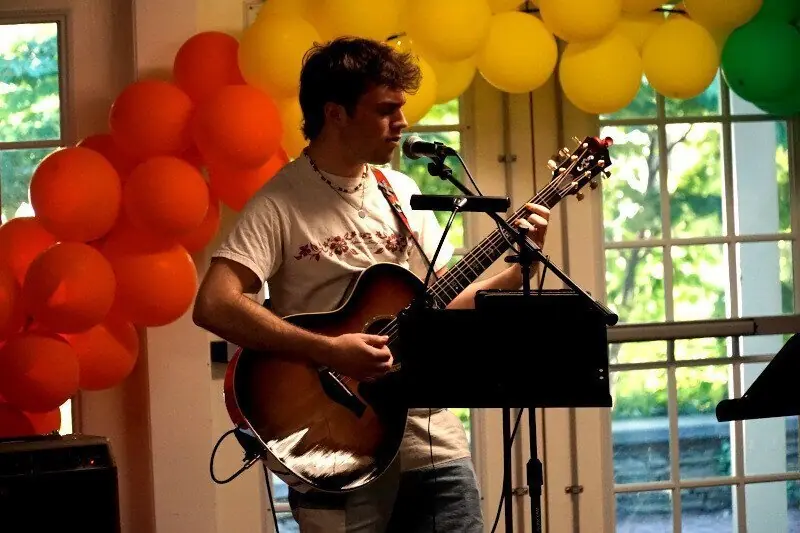 Performer playing at the Open Mic with colorful balloons in the room